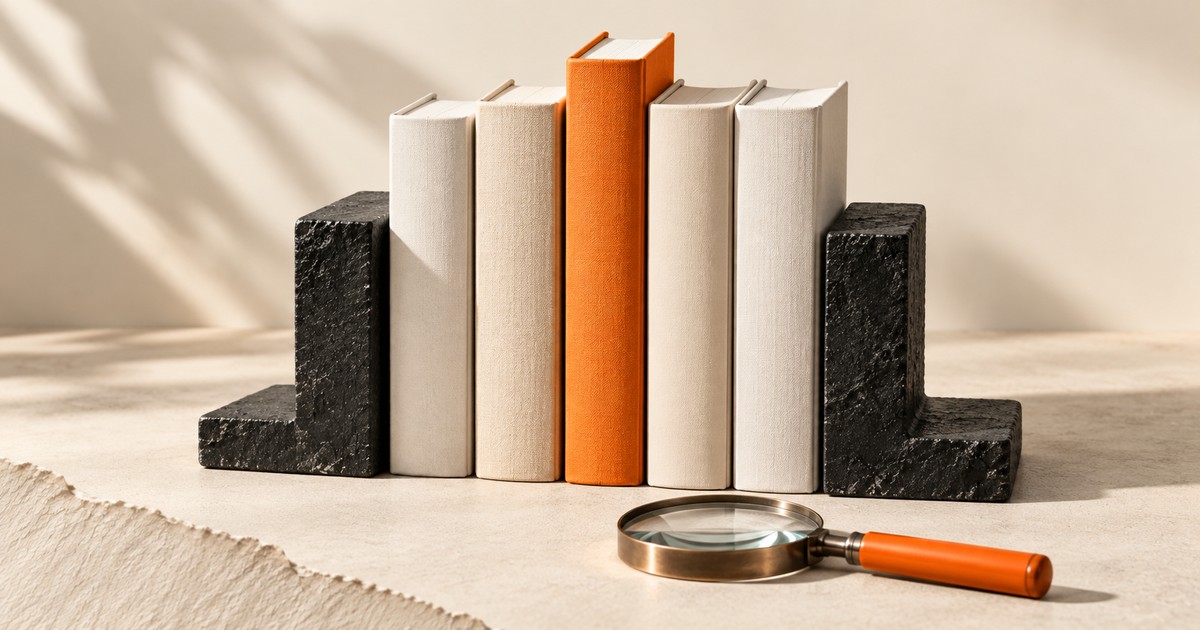 Boş sırtlı kitaplar arasında turuncu kitap ve büyüteç.